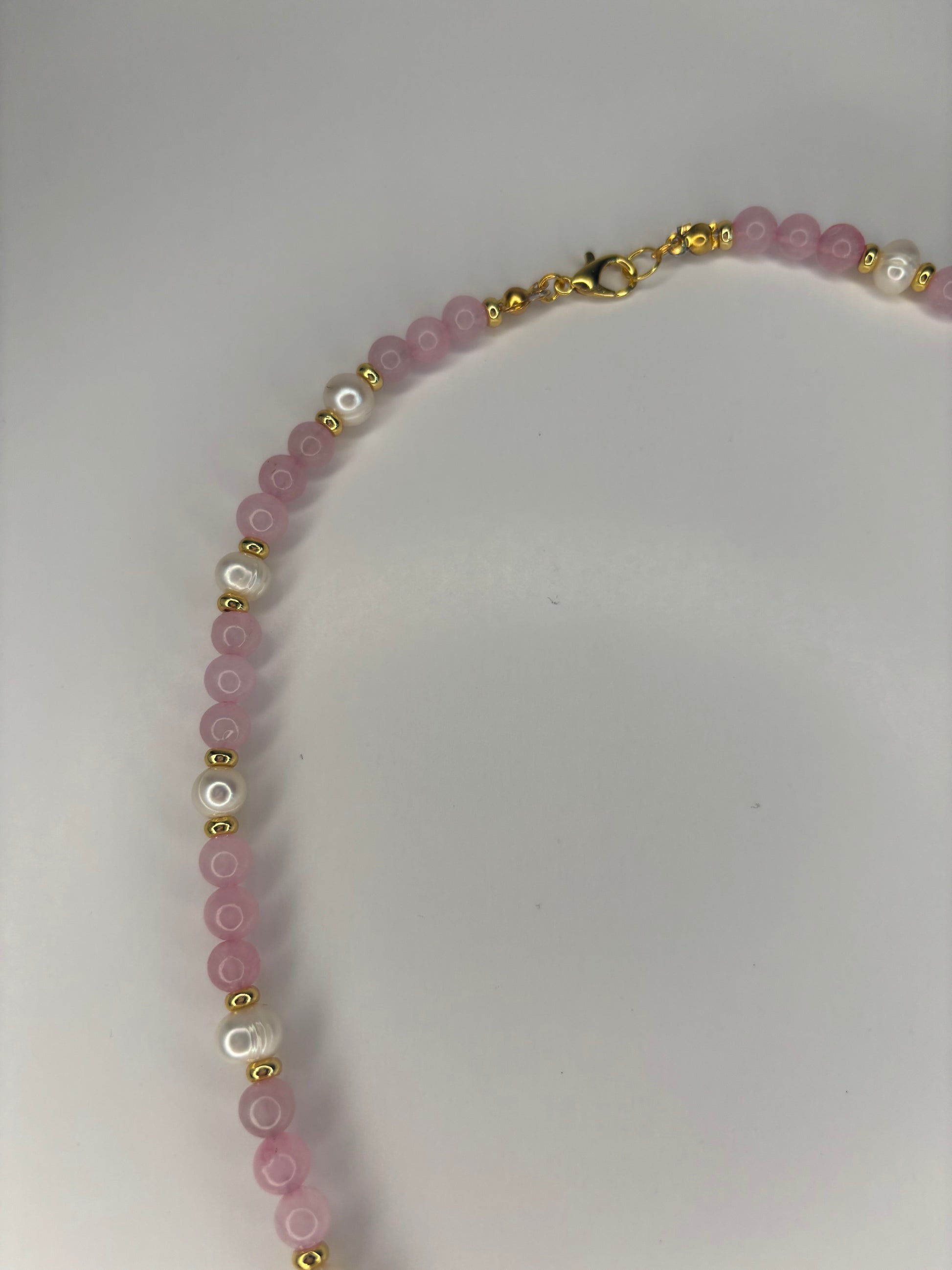 Necklace with pink beads and gold accents on a white background